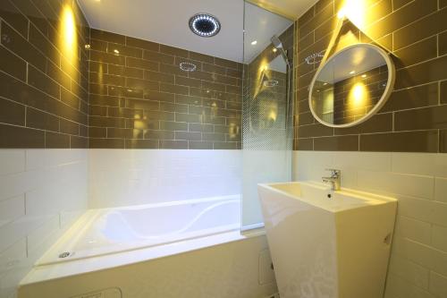 a bathroom with a tub and a sink and a mirror at Brooks Hotel Tongyeong in Tongyeong