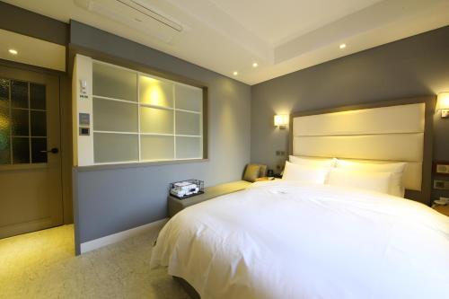 a bedroom with a large white bed and a window at Brooks Hotel Tongyeong in Tongyeong