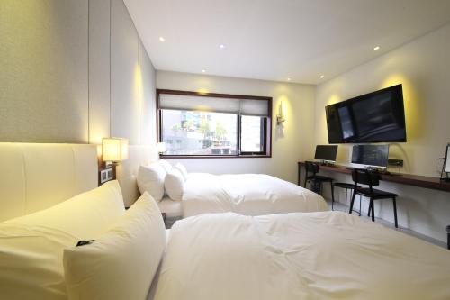 a hotel room with two beds and a flat screen tv at Brooks Hotel Tongyeong in Tongyeong
