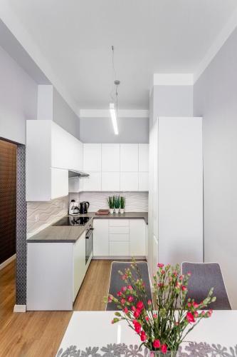 a kitchen with white cabinets and a table at Apartament na Kopernika in Toruń