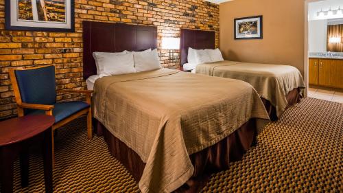 une chambre d'hôtel avec deux lits et une chaise dans l'établissement Best Western State Fair Inn, à Sedalia