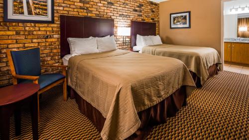 a hotel room with two beds and a chair at Best Western State Fair Inn in Sedalia