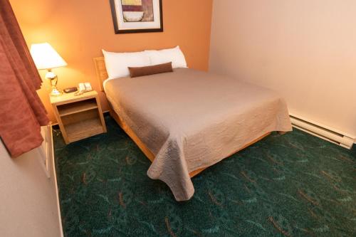 a hotel room with a bed and a table with a lamp at Keystone Motor Inn in Brandon