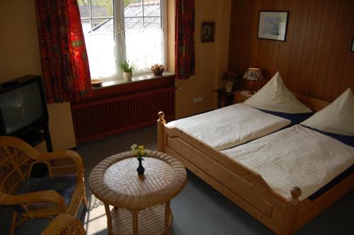 Schlafzimmer mit einem Bett, einem TV und einem Tisch in der Unterkunft Wieting´s Hotel in Esens