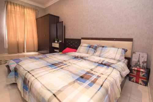 a bedroom with a large bed with a plaid blanket at Skudai Homestay Pulai Perdana near UTM JPO and Taman Universiti in Kampung Kangkar Pulai