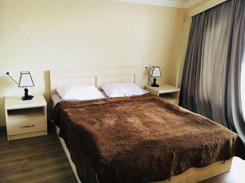 a bedroom with a bed with two night stands and two lamps at Вилла с комфортом in Bakuriani