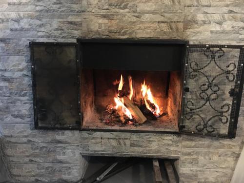 a brick fireplace with a fire in it at Вилла с комфортом in Bakuriani
