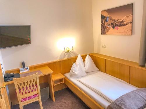 a hotel room with a bed and a desk with a tv at Andi's Skihotel in Obertauern
