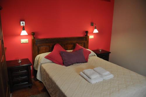 a red bedroom with a bed with towels on it at Casa Rural El Abuelo Quiko in Chinchón