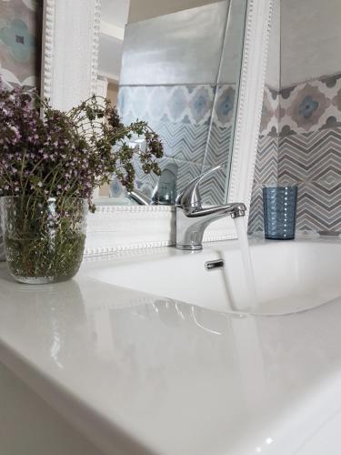 a bathroom sink with a vase of flowers and a mirror at White House in Cagliari