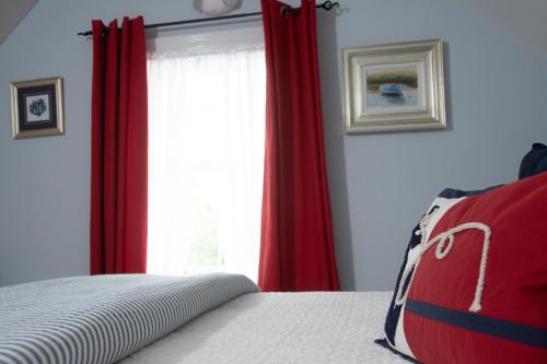 a bedroom with red curtains and a large window at The Ocean Bay House in Bay Shore
