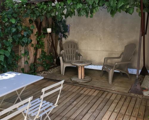 Dos sillas y una mesa en una terraza de madera. en 6A, en Aviñón