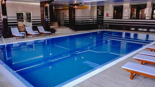 a large swimming pool with blue water and chairs at Hotel International Prishtina & Spa in Pristina