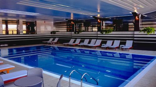 a large swimming pool with chairs and a swimming pool at Hotel International Prishtina & Spa in Prishtinë