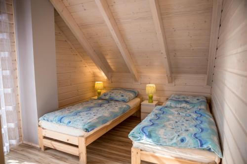 two beds in a room with wooden ceilings at Na Dworosku in Golczowice