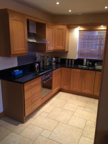 a kitchen with wooden cabinets and black counter tops at Portstewart - holiday let in Portstewart