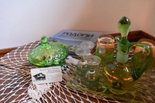 a table with green glass vases and glasses on it at Къща за гости Гайтана in Shiroka Lŭka