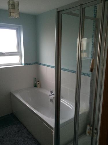 a bathroom with a tub and a glass shower at Portstewart - holiday let in Portstewart