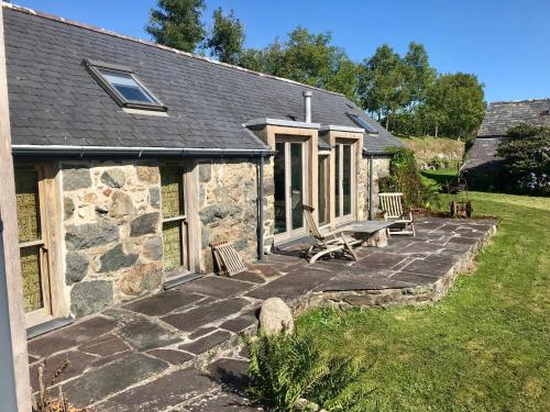una casa in pietra con patio con 2 panche di The Piggery - North Wales Retreat a Pwllheli