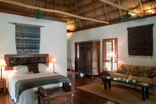 a bedroom with a bed and a couch in a room at Turtle Inn by Francis Ford Coppola in Placencia Village