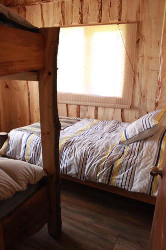 a bed in a wooden room with a window at Karkú Lodge in Pucón