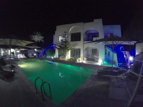 a swimming pool in front of a house at night at Appartement Touta écologique familial in Ḩawmat al Badawīyīn