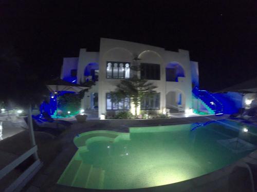 a swimming pool in front of a house at night at Appartement Touta écologique familial in Ḩawmat al Badawīyīn