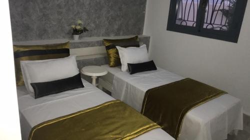 a room with two beds and a table at Appartement Touta écologique familial in Ḩawmat al Badawīyīn