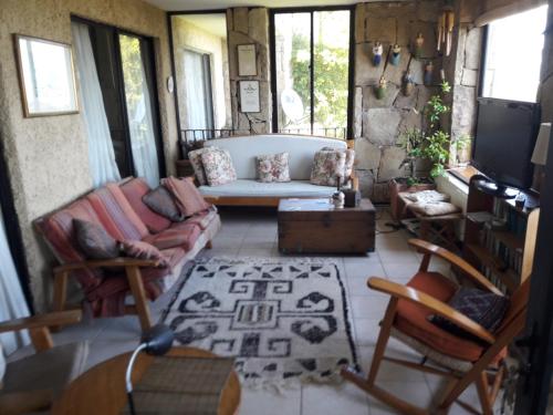 a living room with a couch and chairs and a tv at B&B Santo Domingo Chile ENGLISH SPOKEN Gran Departamento compartido frente al mar PARQUE TRICAO bird sanctuary 14kms 9miles away DESAYUNO ESTACIONAMIENTO Y WIFI GRATIS Free parking wifi and breakfast in Santo Domingo