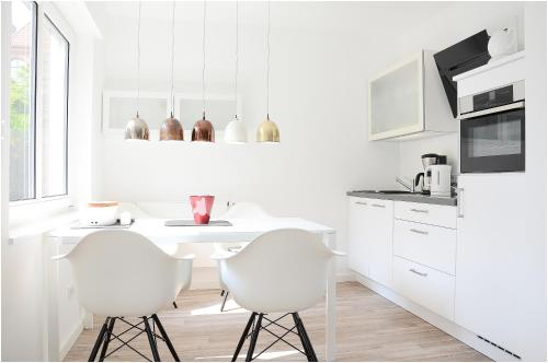 eine weiße Küche mit einem Tisch und 2 weißen Stühlen in der Unterkunft Suite Gartenstraße im hellen Ambiente in Norderney