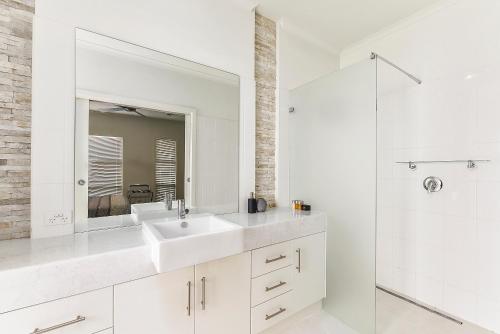 a white bathroom with a sink and a mirror at Urban Corporate Apartment in Mount Gambier
