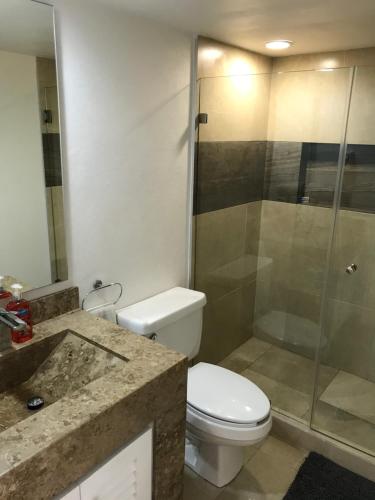 a bathroom with a toilet and a glass shower at Departamento 522 con playa dentro de Hotel en Ixtapa in Ixtapa