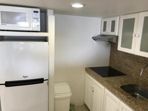 a small kitchen with a white refrigerator and a microwave at Departamento 522 con playa dentro de Hotel en Ixtapa in Ixtapa