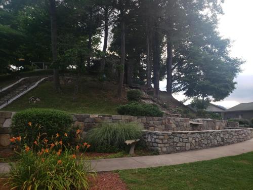 a stone retaining wall in a yard with trees at Nantahala Village in Bryson City