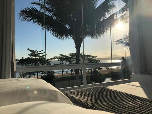 a bedroom with a view of the beach and palm trees at Pousada Caravelas in Guarapari