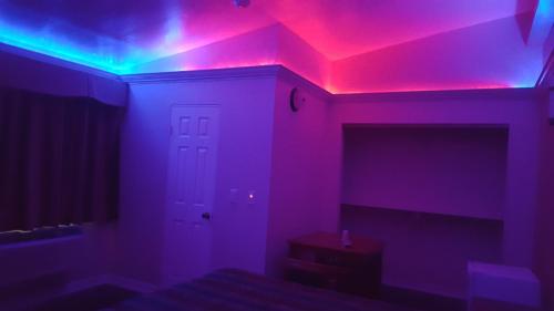 a bedroom with pink and blue lights on the ceiling at Deluxe Motel, Los Angeles Area in Downey