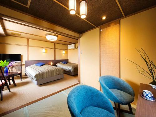 a bedroom with two beds and blue chairs in it at Asahiro in Minabe