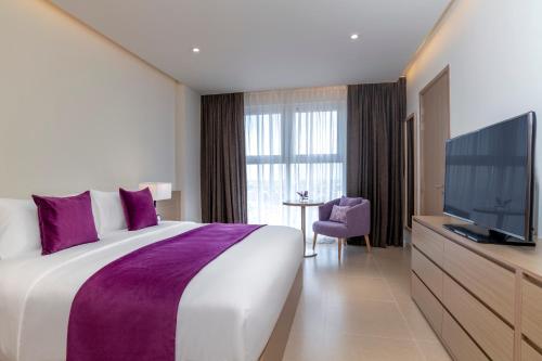 a hotel room with a large bed and a flat screen tv at Mercure Hai Phong in Hai Phong