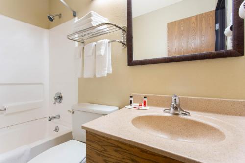 a bathroom with a sink and a toilet and a mirror at Super 8 by Wyndham Weston WV in Weston