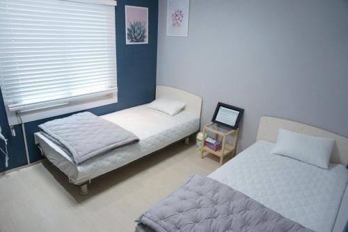 a bedroom with two beds and a window with a laptop at AIRPORT Guesthouse in Busan