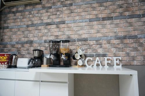 a white table with a coffee maker and a brick wall at AIRPORT Guesthouse in Busan