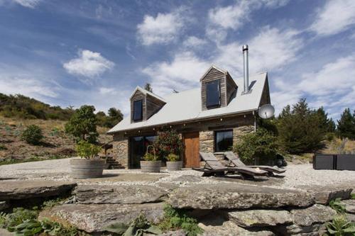a small stone house with a bench in front of it at Creagh Cottage and Homestead in Arrowtown