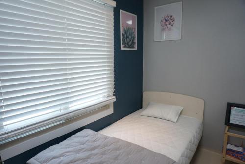 a small bedroom with a bed and a window at AIRPORT Guesthouse in Busan