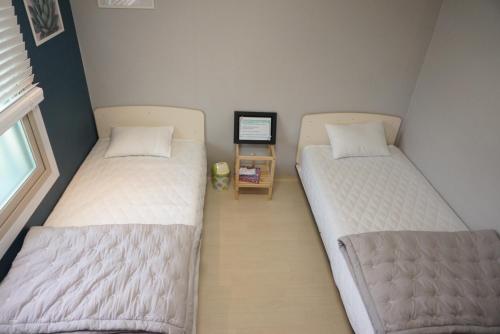 two beds in a room with a computer on a table at AIRPORT Guesthouse in Busan