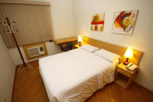 a bedroom with a large white bed and two lamps at London Class Hotéis in Sao Paulo