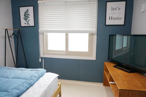 a living room with a window and a television at AIRPORT Guesthouse in Busan