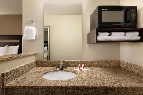 a bathroom with a sink and a microwave at Baymont by Wyndham Wellington in Wellington