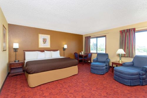 a hotel room with a bed and two chairs at AmericInn by Wyndham West Bend in West Bend