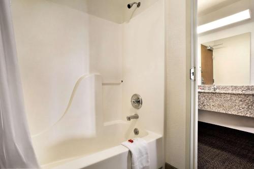 a white bathroom with a tub and a sink at Travelodge by Wyndham Cheyenne in Cheyenne