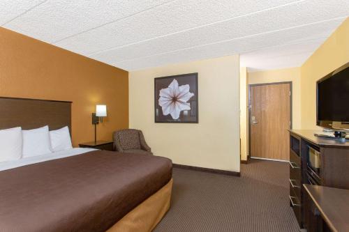 a hotel room with a bed and a flat screen tv at AmericInn by Wyndham West Bend in West Bend